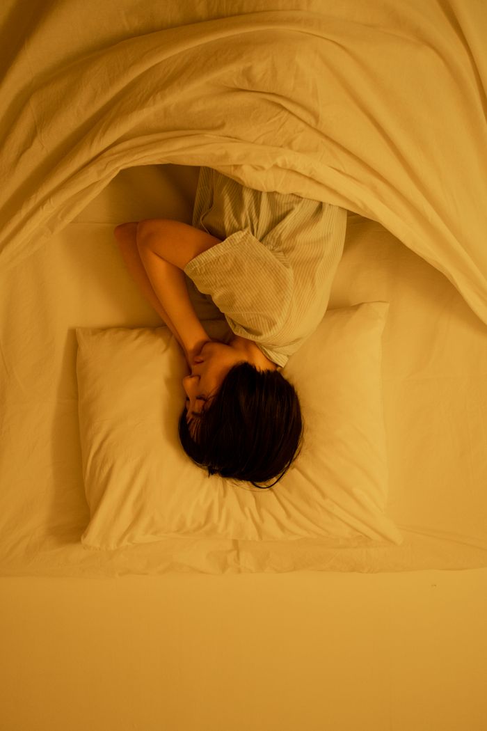 A calm scene of a young adult sleeping peacefully in a bed, showcasing relaxation.