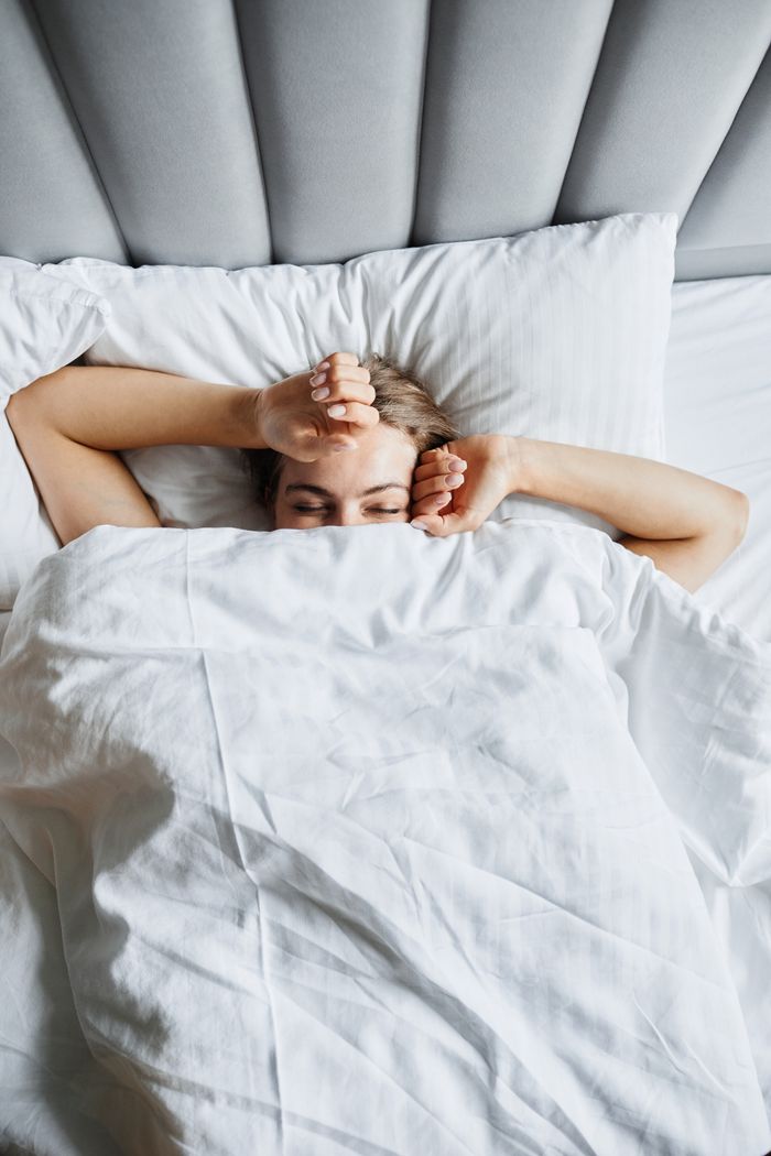 Woman comfortably resting in bed, enjoying a peaceful morning under the covers.